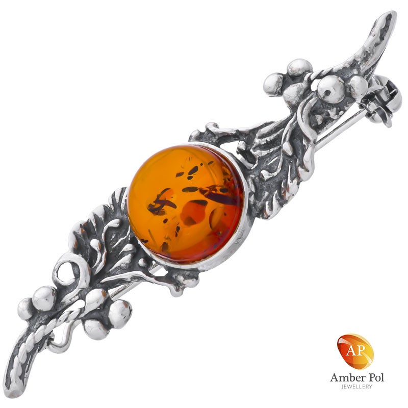 Broszka srebrna 925 z bursztynem w kolorze koniaku ,otoczonym srebrnymi zdobieniami na całej długości.