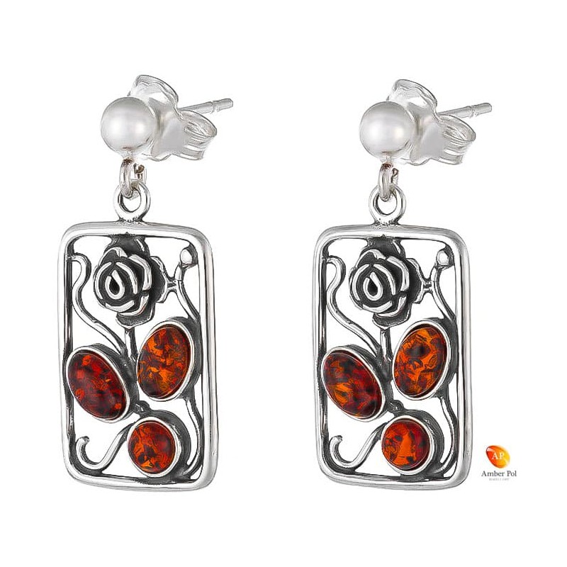 Kolczyki wiszące ze srebra 925 o kształcie ramki z różą na zawieszce typu bigiel zapinany i z trzema koniakowymi bursztynami.