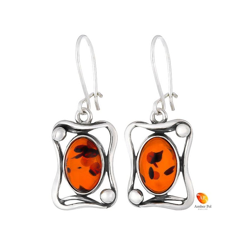 Kolczyki wiszące ze srebra 925 na zawieszce bigiel zapinany  z owalnym  koniakowym bursztynem umieszczonym w zdobionej ramce.