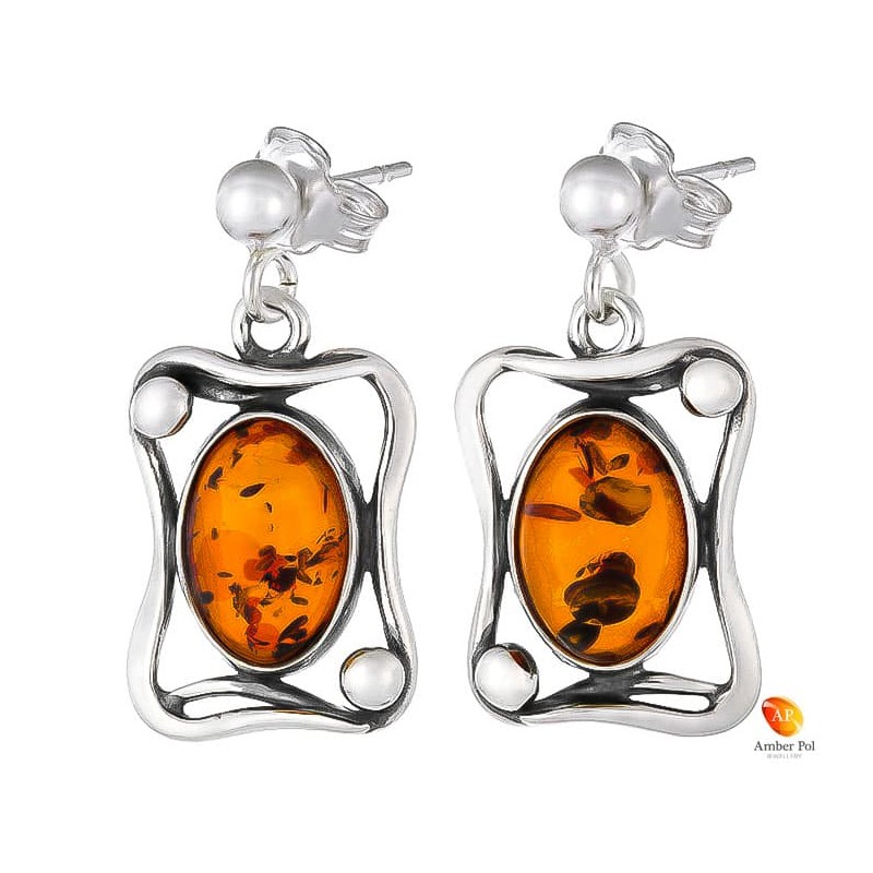 Kolczyki wiszące ze srebra 925 na zawieszce na sztyft z kulką z owalnym  koniakowym bursztynem umieszczonym w zdobionej ramce.