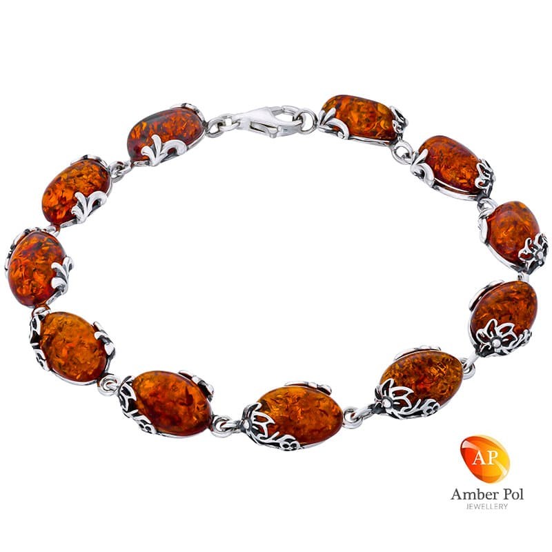 Piękna srebrna bransoletka próby 925 z 11 elementami i owalnymi  bursztynami w kolorze koniaku. Zdobiona ażurkami.