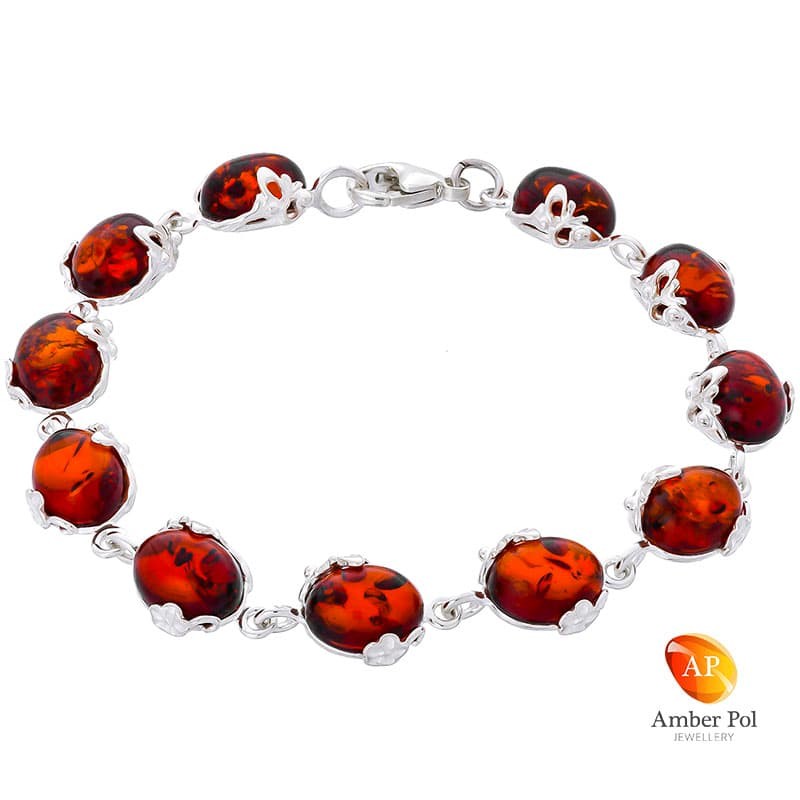 Piękna srebrna bransoletka próby 925 z 11 elementami i owalnymi  bursztynami w kolorze koniaku. Zdobiona ażurkami.