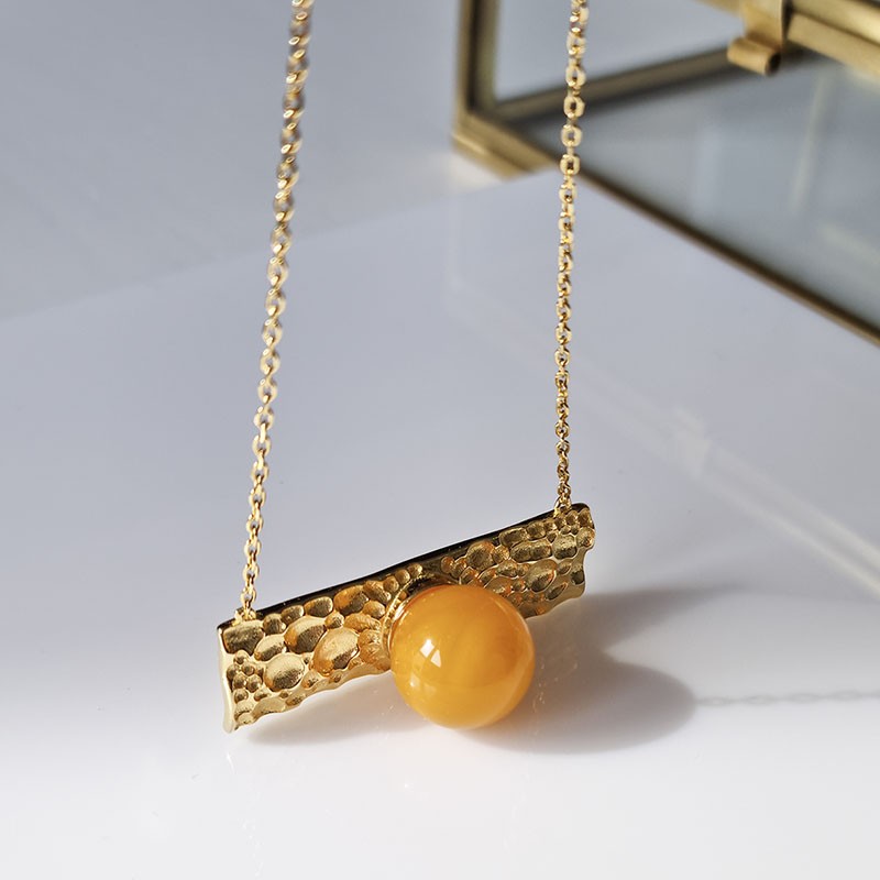 Naszyjnik ze srebra 925 pozłocony 24 karatowym złotem  ozdobnym panelem i bursztynową kulką w mlecznym kolorze.