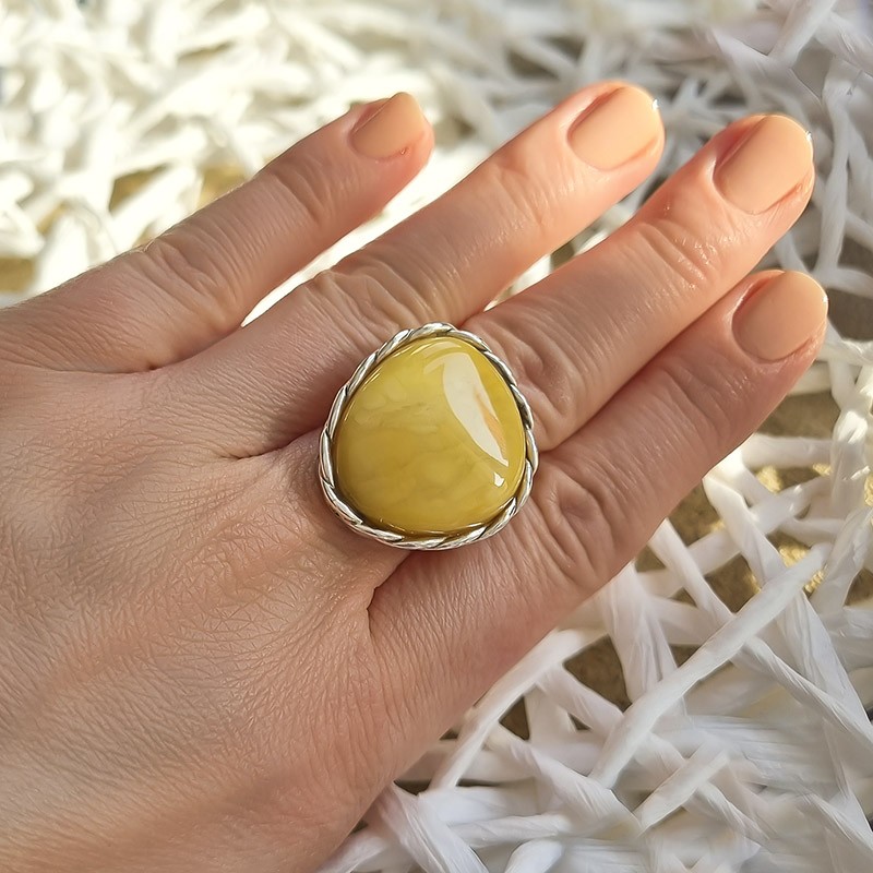Unikatowy pierścionek ze srebra 925 z dużym bursztynem w żółtym kolorze ozdobionym plecioną oprawą.